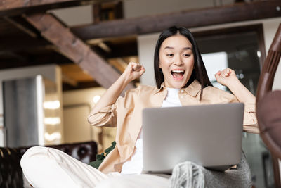 Portrait of young woman using laptop while sitting at home