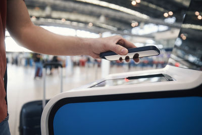 Hand of man using self service check-in. passenger scanning ticket on phone at airport terminal.