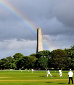 People on field by trees against sky