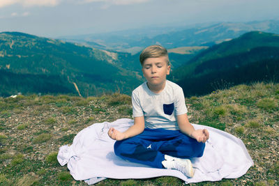 Full length of boy sitting on field