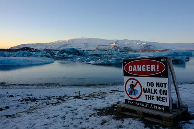 Information sign on snow covered mountain against sky