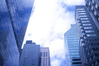 Low angle view of skyscrapers against cloudy sky