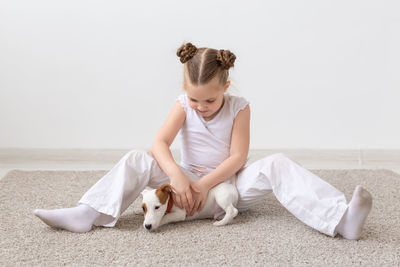 Young woman with dog sitting on sofa against white background