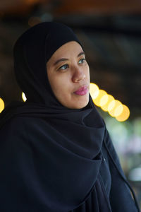 Portrait of indonesian muslim woman wearing black hijab with bokeh.