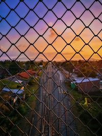 Close-up of chainlink fence against sky during sunset