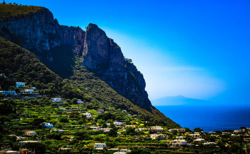 Scenic view of sea by buildings against blue sky