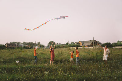 Happy family and children run on meadow with a kite in the summer on the nature.