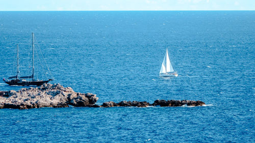 Sailboat sailing in sea against blue sky