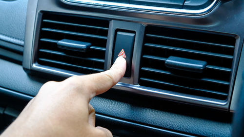 Cropped hand of person pressing button in car