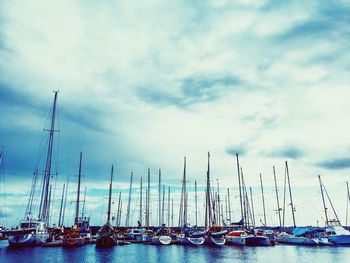 Boats in harbor against cloudy sky