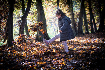 Girl kicking leaves in forest