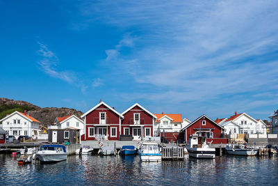 Boats moored at harbor by buildings against sky