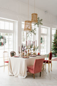 Beautifully laid table for christmas dinner in a classic living room with french windows christmas