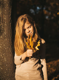 Teenage girl with freckles on a walk among yellow leaves in autumn