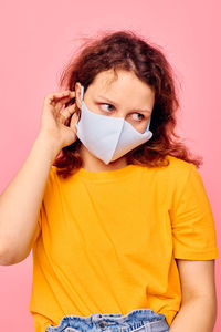 Young woman wearing hat against yellow background