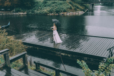 Rear view of woman standing by railing against lake