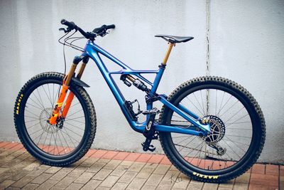 Bicycle parked on sidewalk against wall