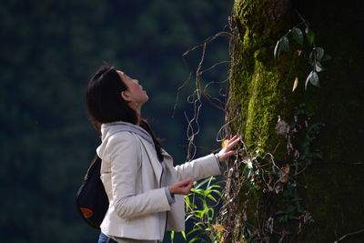 Woman standing against moss wall