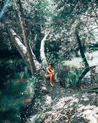 Man sitting by tree trunk in forest