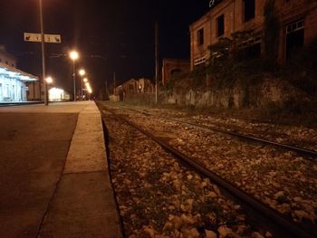 Surface level of railroad tracks amidst buildings at night