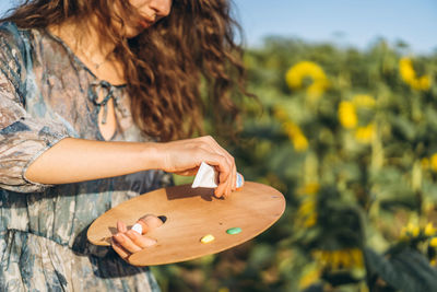 Midsection of woman holding umbrella on field