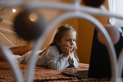 Child watching cartoons on laptop. serious kid with technology at home on bed spending time on-line