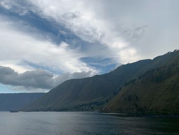 Scenic view of lake by mountains against sky