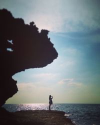 Silhouette of people standing on beach at sunset