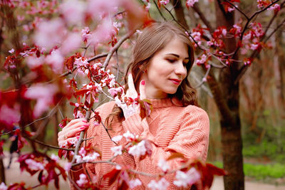 Beautiful woman standing under pink blossom tree
