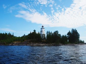 Lighthouse by sea against sky