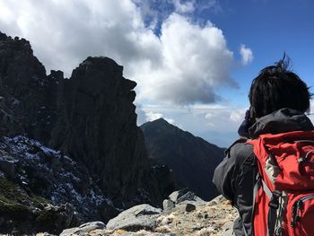 Rear view of man standing on rock against sky