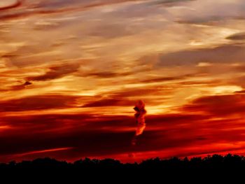 Silhouette trees against dramatic sky during sunset