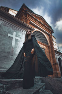 Woman standing by cross against sky