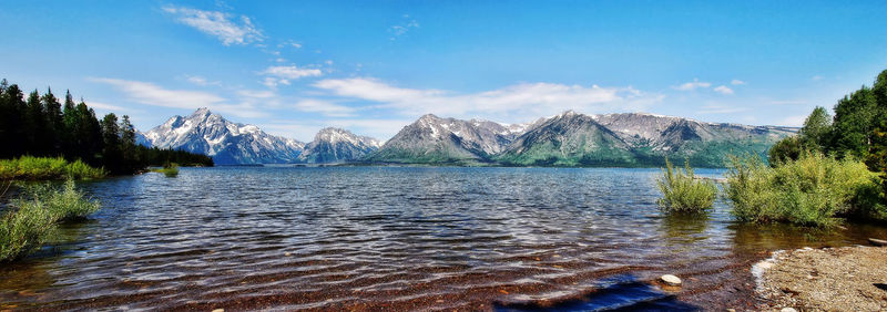 Scenic view of lake and mountains against blue sky