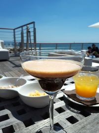 Close-up of beer on table by sea against sky