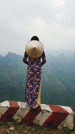 Rear view of woman standing on land against sky