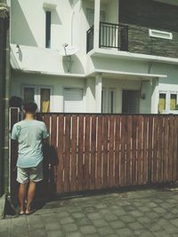 Rear view of man walking on street against building