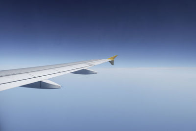 Airplane wing against clear blue sky