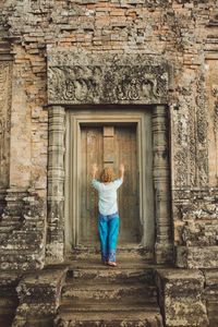 Rear view of woman standing against old building