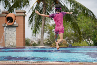 Rear view of girl jumping in swimming pool