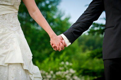 Midsection of bride and bridegroom holding hands