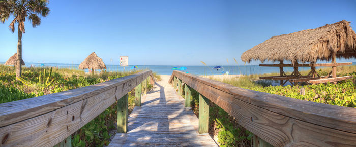 Footpath leading towards sea against clear sky