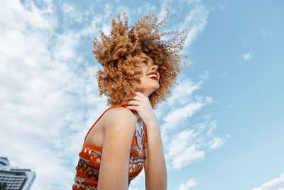 Portrait of young woman standing against sky