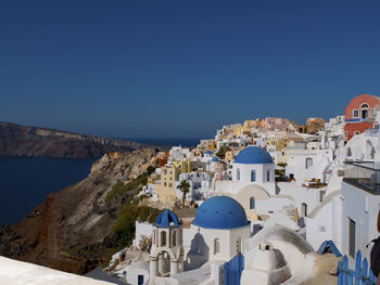 Townscape by sea against clear blue sky