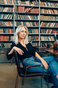 Full length of young woman sitting on book