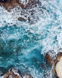 High angle view of sea waves rushing on rock formation 