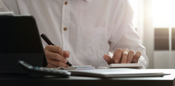 Midsection of man using mobile phone on table