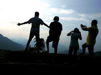 Friends standing on mountain against sky