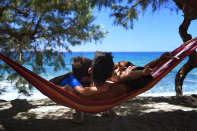 Father with children relaxing in hammock at beach