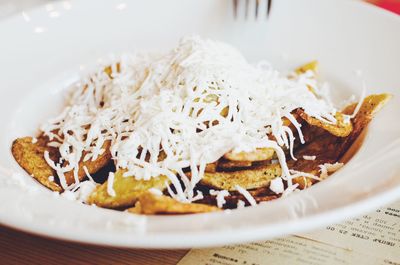 French fries garnished with cheese served in plate on table